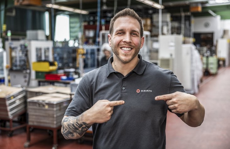 Mitarbeiter zeigt auf Logoaufdruck auf T-Shirt von Kern Antriebstechnik